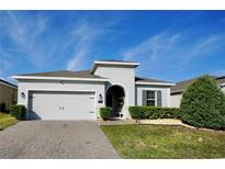 Charming home with a two-car garage, well-maintained lawn, and beautifully designed gray brick driveway at 916 Carmillion Ct, Groveland, FL 34736
