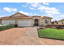 Beautiful single-story home with brick driveway, well-manicured landscaping, and a two-car garage at 10199 Mainsail Dr, Oxford, FL 34484