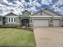 Charming single Gathering home featuring a three car garage, well manicured lawn, and stone accents at 142 Bayou Bend Rd, Groveland, FL 34736