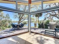 Bright sunroom with floor-to-ceiling windows offering stunning lake views and access to the deck at 1617 Lake Nettie Ct, Eustis, FL 32726