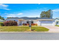 Charming single-story home with a well-manicured lawn, brick accents, and an attached two-car garage at 17594 Se 95Th Cir, Summerfield, FL 34491