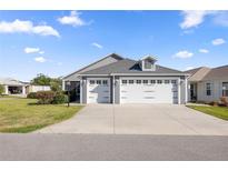 Charming home featuring a three-car garage and well-manicured lawn on a sunny day at 1853 Pasqua Pl, The Villages, FL 32163