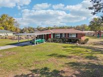 Charming single-story brick home with a well-manicured lawn and covered parking at 231 Cr 482S, Lake Panasoffkee, FL 33538