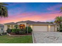 Charming single-story home with a three-car garage, lush landscaping, and a brick-paved driveway at 2428 Maverick Way, The Villages, FL 32162