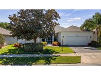 Charming single-story home with a well-manicured lawn, lush landscaping, and a two-car garage at 3728 Mulberry Grove Loop, Leesburg, FL 34748