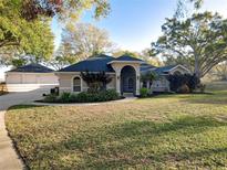 Charming single-story home featuring mature landscaping, a circular driveway, and a separate garage in a lush neighborhood at 5813 Lake Emma Ct, Groveland, FL 34736