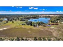 Stunning aerial view of a large estate featuring a private lake and outbuildings on a vast property at 6988 Blue Cedar Rd, Leesburg, FL 34748