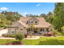 Inviting home featuring a stone facade, charming porch, and lush landscaping at 7636 Lake Angelina Dr, Mount Dora, FL 32757