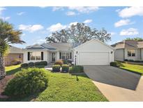 Charming single-story home with a well-manicured lawn and attached two-car garage on a sunny day at 1419 Valparaiso St, The Villages, FL 32162