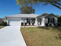 Charming one-story home with well-manicured lawn, bright white driveway, and attached two-car garage at 2250 Peak Pl, The Villages, FL 32162