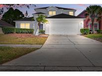 Charming two-story home with a two-car garage and well-maintained landscaping with small palm tree at 4703 Golden Beach Ct, Kissimmee, FL 34746