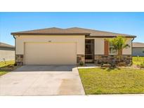 Charming single-story home with stone accents, a well-manicured lawn, and an attached two-car garage at 1188 Oak Valley Dr, Auburndale, FL 33823