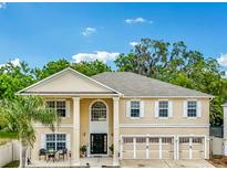 Two-story home with a three-car garage, columns, and large front windows, creating a bright and welcoming facade at 1454 Sterns Dr, Leesburg, FL 34748