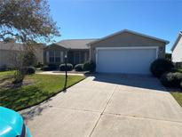 Charming single-story home features a manicured lawn, mature landscaping, and a two-car garage at 2746 Edwards Ln, The Villages, FL 32162