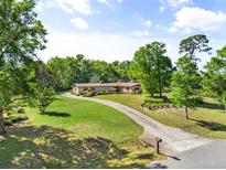 Sprawling ranch-style home features a long driveway, lush lawn, and mature trees providing shade and privacy at 3452 N Washington St, Zellwood, FL 32798