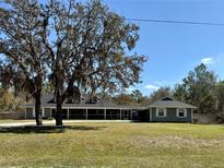 Charming home featuring a screened-in porch, lush lawn, and mature trees, perfect for relaxing outdoors at 42836 Royal Trails Rd, Eustis, FL 32736