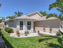 Charming single-story home featuring a well-manicured lawn, potted plants, and bright exterior paint at 5441 Sea Leopard St, Tavares, FL 32778