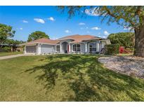 Charming single-story home with a well-manicured lawn, bright red door, and elegant architectural details at 8925 Pebble Beach Pl, Clermont, FL 34711