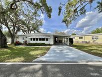 Charming single-story home featuring a carport, manicured lawn, and mature trees offering shade and curb appeal at 101 Poinsettia Cv, Leesburg, FL 34748
