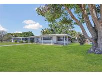 Charming single-story home with a well-maintained lawn and a large tree providing shade at 1112 Elkhart Cir, Tavares, FL 32778