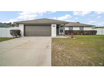 Well-maintained single-story home featuring a two-car garage and a neatly landscaped front yard at 12370 Se 100Th Ct, Belleview, FL 34420