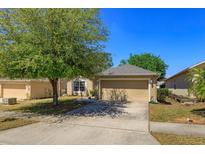Charming single-Gathering home with a well-maintained lawn and a two-car garage on a sunny day at 129 Cabrillo Dr, Groveland, FL 34736