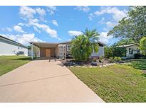 Charming single-story home with a carport, well-manicured lawn, and beautiful landscaping, perfect for curb appeal at 1541 Doral Cir, Lady Lake, FL 32159