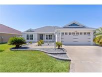 Charming home featuring a well-manicured lawn, beautiful landscaping, and an attached two car garage at 1589 Armstrong Ave, The Villages, FL 32163