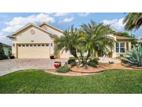 Charming home featuring manicured landscaping, a brick driveway, a two-car garage, and elegant palm trees at 17066 Se 111Th Ter, Summerfield, FL 34491