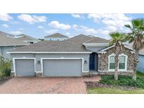 Charming single-Gathering home with three-car garage, stone accents, brick-paved driveway, and well-manicured landscaping at 3193 Hill Point St, Minneola, FL 34715