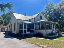 Charming two-story home with a screened porch and metal roof in a serene, tree-lined setting at 510 E Orange Ave, Eustis, FL 32726