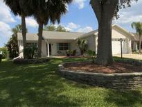 Charming single-story home with well-maintained lawn and landscaping including a tree and several palms at 664 San Pedro Dr, The Villages, FL 32159