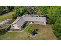 Aerial view of a ranch-style home with stone accents, metal roof, and a backyard pool at 6745 State Road 33, Clermont, FL 34714