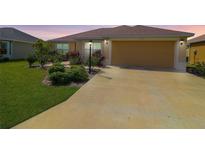 Charming single-story home boasts a well-manicured lawn, lovely landscaping, and a two-car garage at 886 Hubbard Loop, The Villages, FL 32163