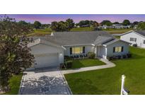 Beautiful white house with a well-manicured lawn and a charming driveway design at 9948 Se 175Th Pl, Summerfield, FL 34491