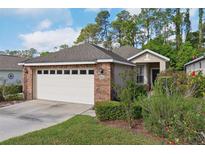 Charming single-Gathering home with brick facade, two-car garage, and landscaped front yard at 1022 Saint Ives Ct, Mount Dora, FL 32757
