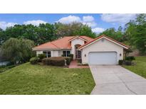 Charming single-story home with a Spanish tile roof, lush lawn, and mature landscaping at 11497 Sw 82Nd Court Rd, Ocala, FL 34481