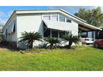 Charming single-story home with a well-maintained lawn and awning with covered parking on a sunny day at 121 Maple Dr, Debary, FL 32713