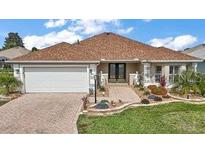 Charming home with a brick driveway, well-manicured lawn, and a welcoming front entrance at 1210 Weaton Ct, The Villages, FL 32162