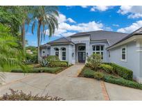 Beautiful single-story home with a well-manicured lawn and a grand front entrance with decorative palm trees at 13112 Luntz Point Ln, Windermere, FL 34786