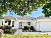 Charming single-story home with a well-maintained lawn, pink accents, and lush landscaping at 1312 Corona Ave, The Villages, FL 32159