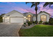 Charming home featuring a lush green lawn, manicured landscaping, and a paver driveway at 1992 Hagood Loop, The Villages, FL 32162