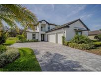 Beautiful two-story home showcasing a well-manicured lawn, palm trees, and a spacious three-car garage with a stone driveway at 25962 High Hampton Cir, Sorrento, FL 32776