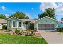 Charming one-story home with beautiful landscaping, lush lawn, and a screened two-car garage on a sunny day at 4717 Inverness Dr, Leesburg, FL 34748