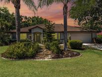 Charming one-story home with well-manicured lawn and lush landscaping featuring palm trees and decorative rock garden at 5906 Prince Philip Ct, Leesburg, FL 34748