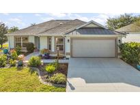 Charming single-story home with a well-manicured lawn and a two-car garage with a retractable screen at 1061 Woodruff St, The Villages, FL 32162