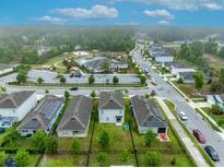 Community aerial view featuring a pool, surrounding houses and street in a neighborhood with verdant green space at 113 Camilla Rd, Deland, FL 32724