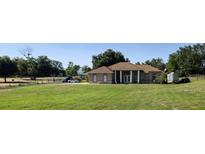 A single-story home boasts a sprawling lawn, complemented by mature trees, and a columned entryway at 13013 County Road 561A, Clermont, FL 34715