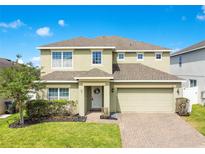 Charming two-story home featuring a brick driveway, neutral siding, manicured landscaping, and an attached two-car garage at 161 Williamson Dr, Davenport, FL 33897