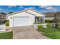 Charming single-story home with a well-manicured lawn, white picket fence, and a two-car garage at 17428 Se 82Nd Albemarle Ave, The Villages, FL 32162